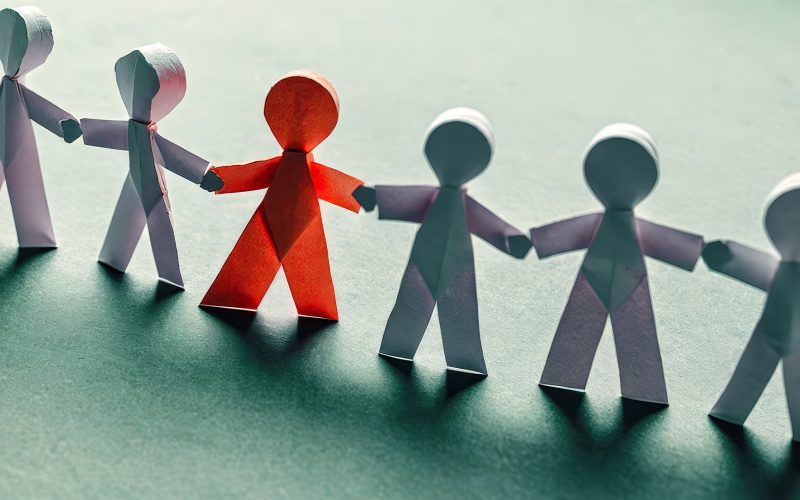Colorful paper cutout figures holding hands, symbolizing unity, diversity, equality, on blue background, representing community support, collaboration, inclusivity, teamwork, multicultural society Diverse paper people chain on blue surface, inclusion, unity, teamwork. symbolize equal rights, community support, harmonious multicultural society. Concept solidarity, partnership, togetherness